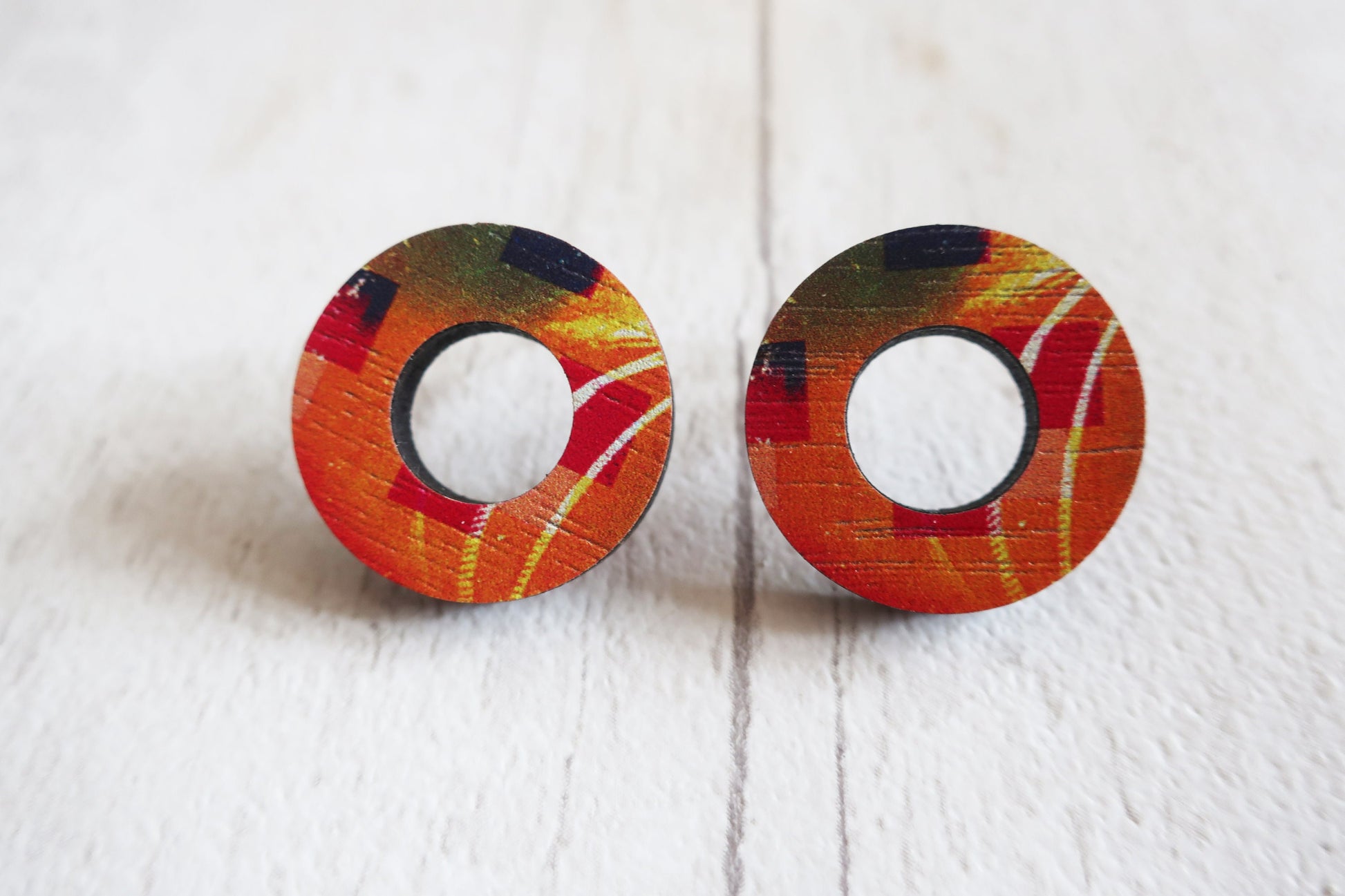 Pair of round earrings with colorful design on a white background