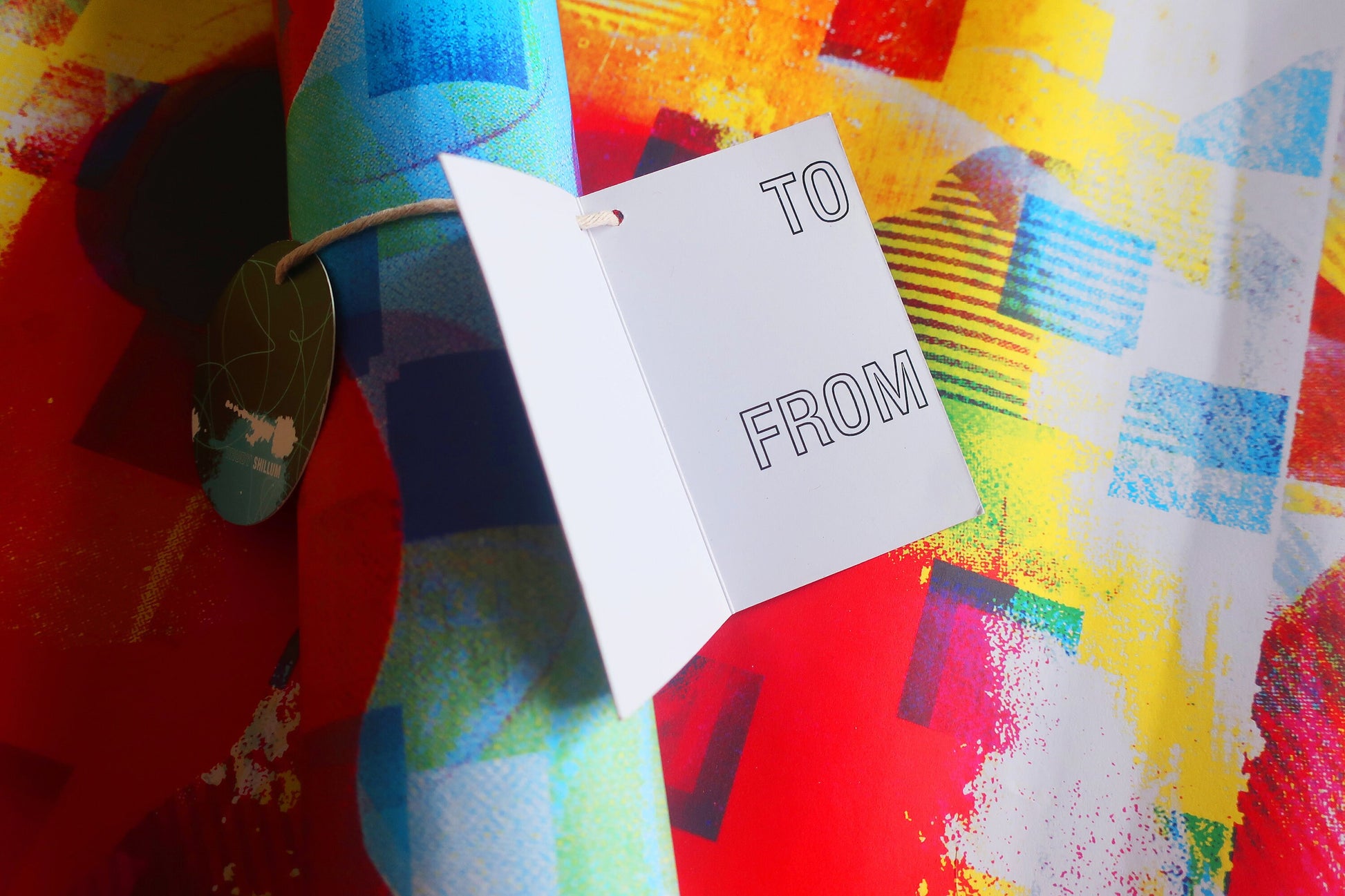 Gift tag with 'TO' and 'FROM' text on a colorful abstract background