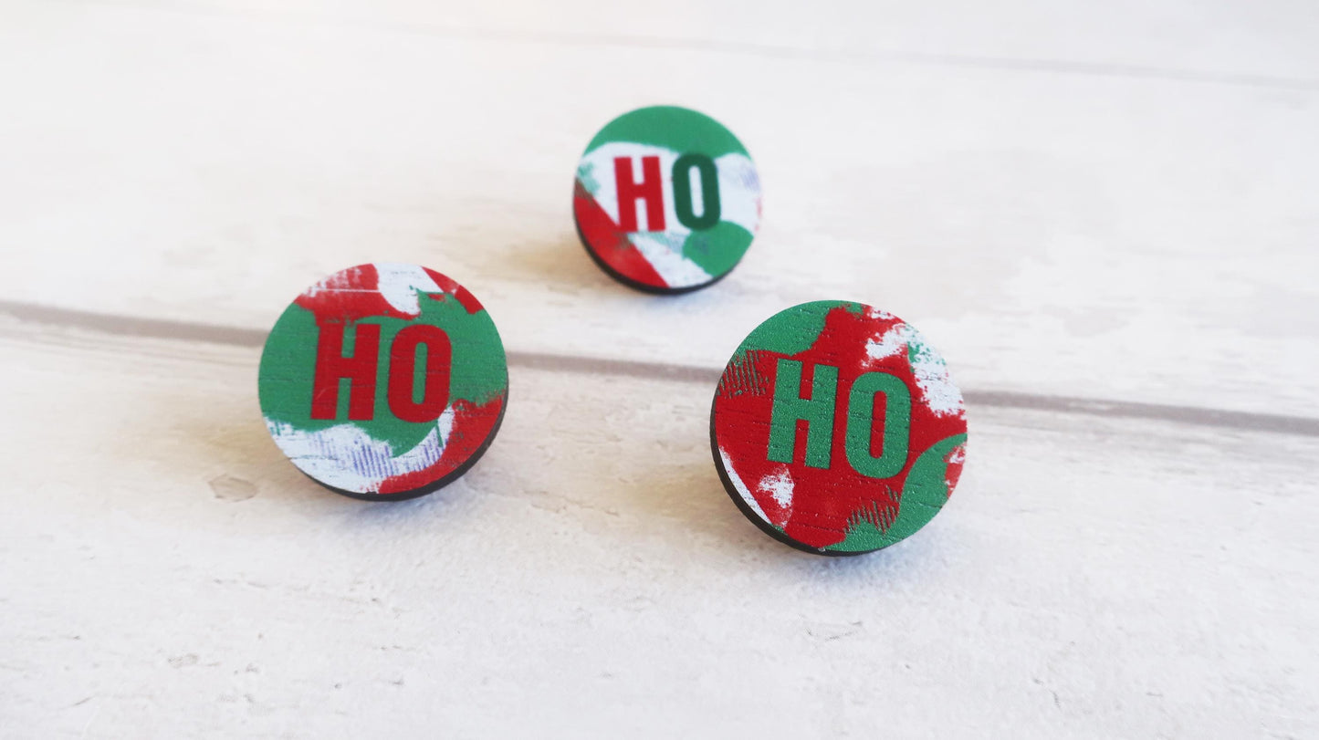 Three round Christmas-themed pin badges with 'HO' text on a white background