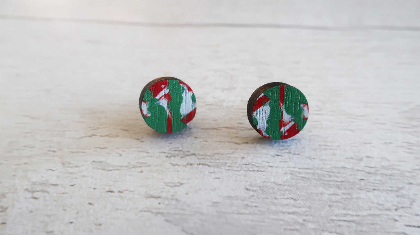 Pair of round earrings with a red and green pattern on a light wooden surface.