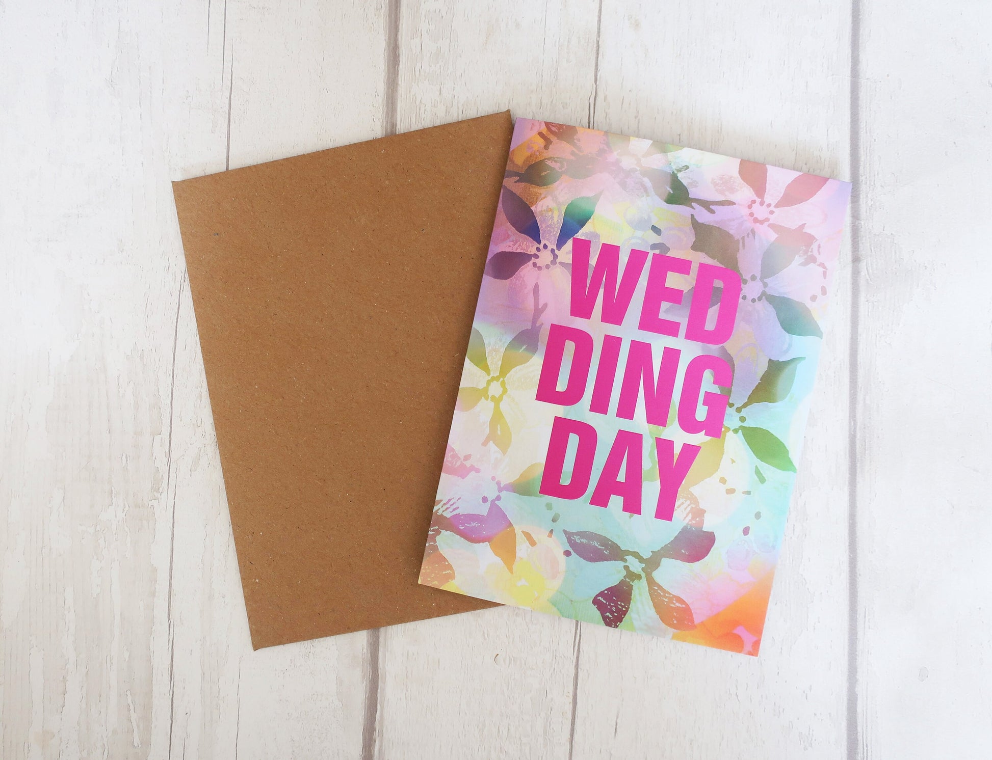 Card with 'Wedding Day' text on a floral pattern next to a plain card on a wooden surface