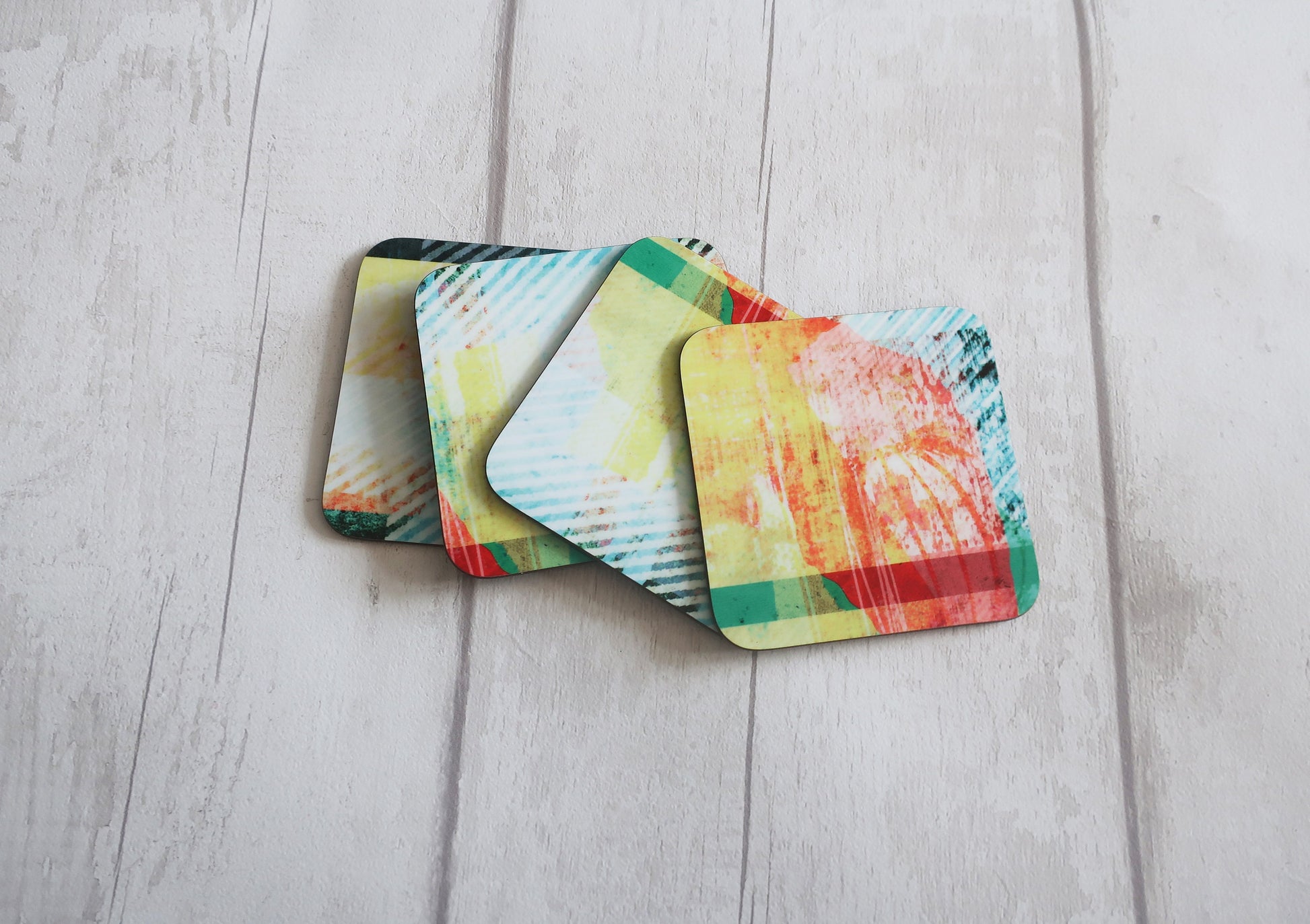 Four colorful coasters on a light wooden surface