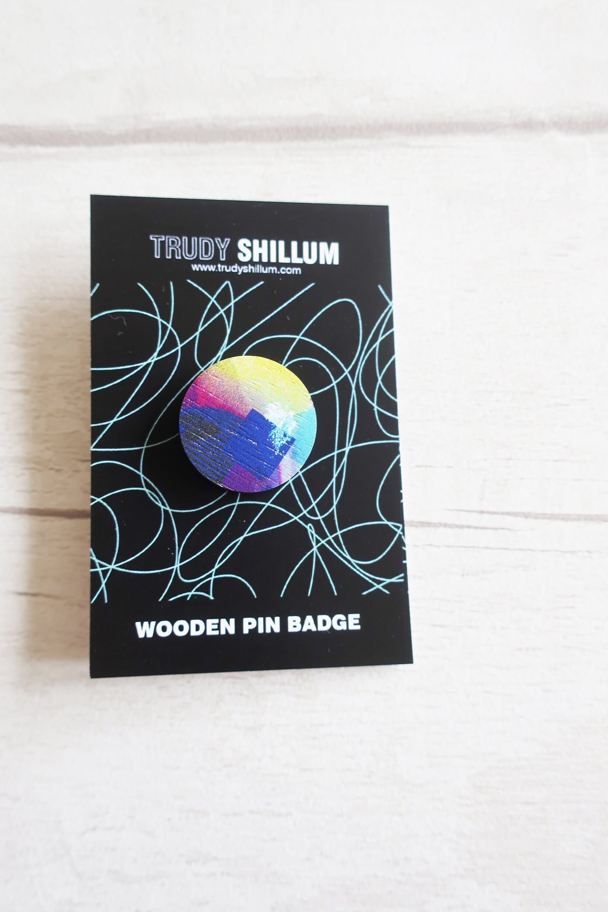 Trudy Shillum wooden pin badge on a black card with a white background