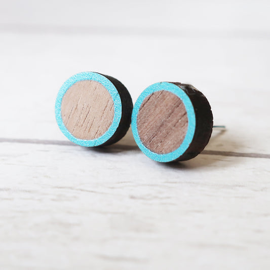 Round wooden earrings with turquoise rim on a light gray background