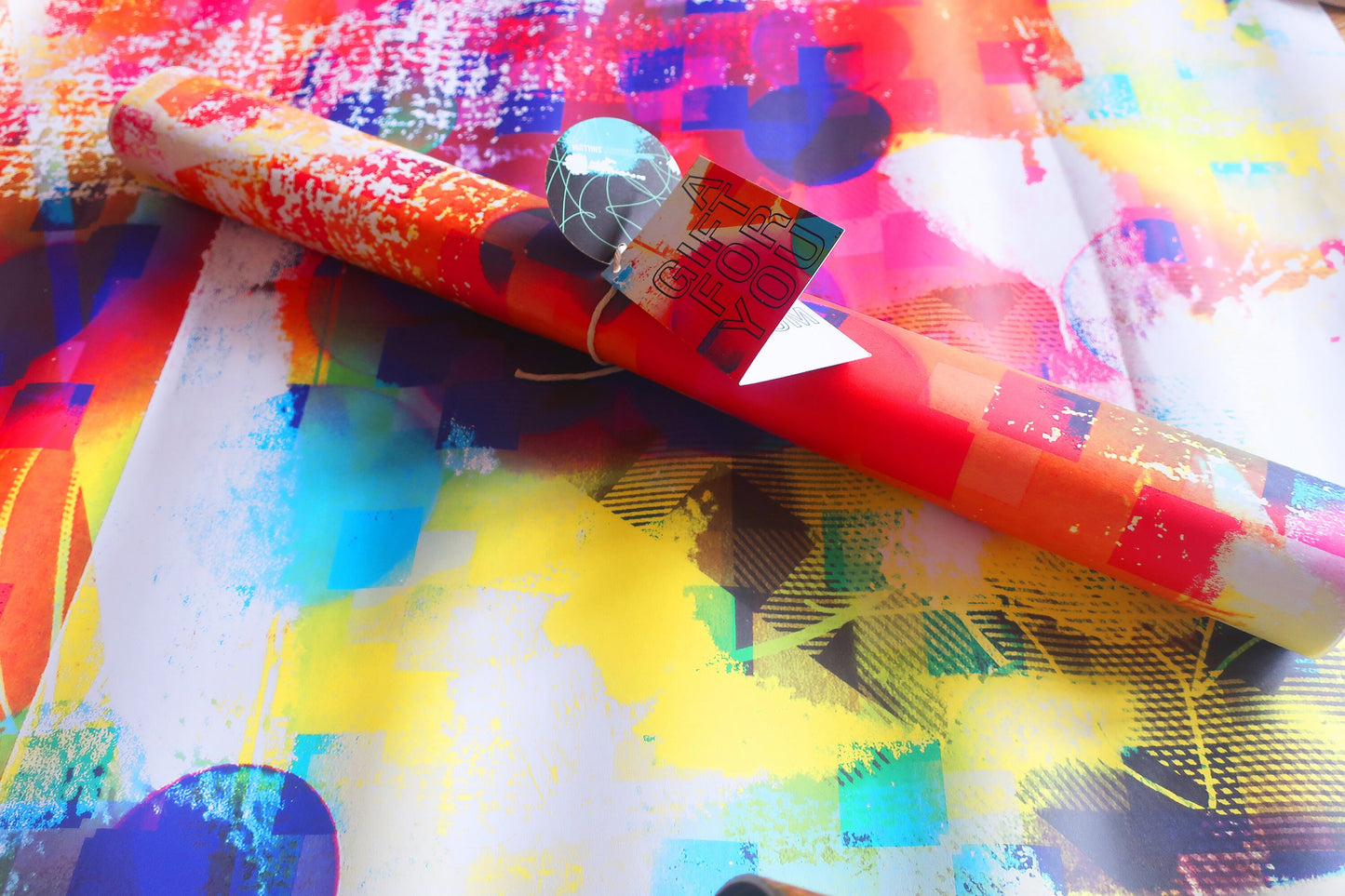 Colorful wrapping paper with abstract patterns and a small red box on top