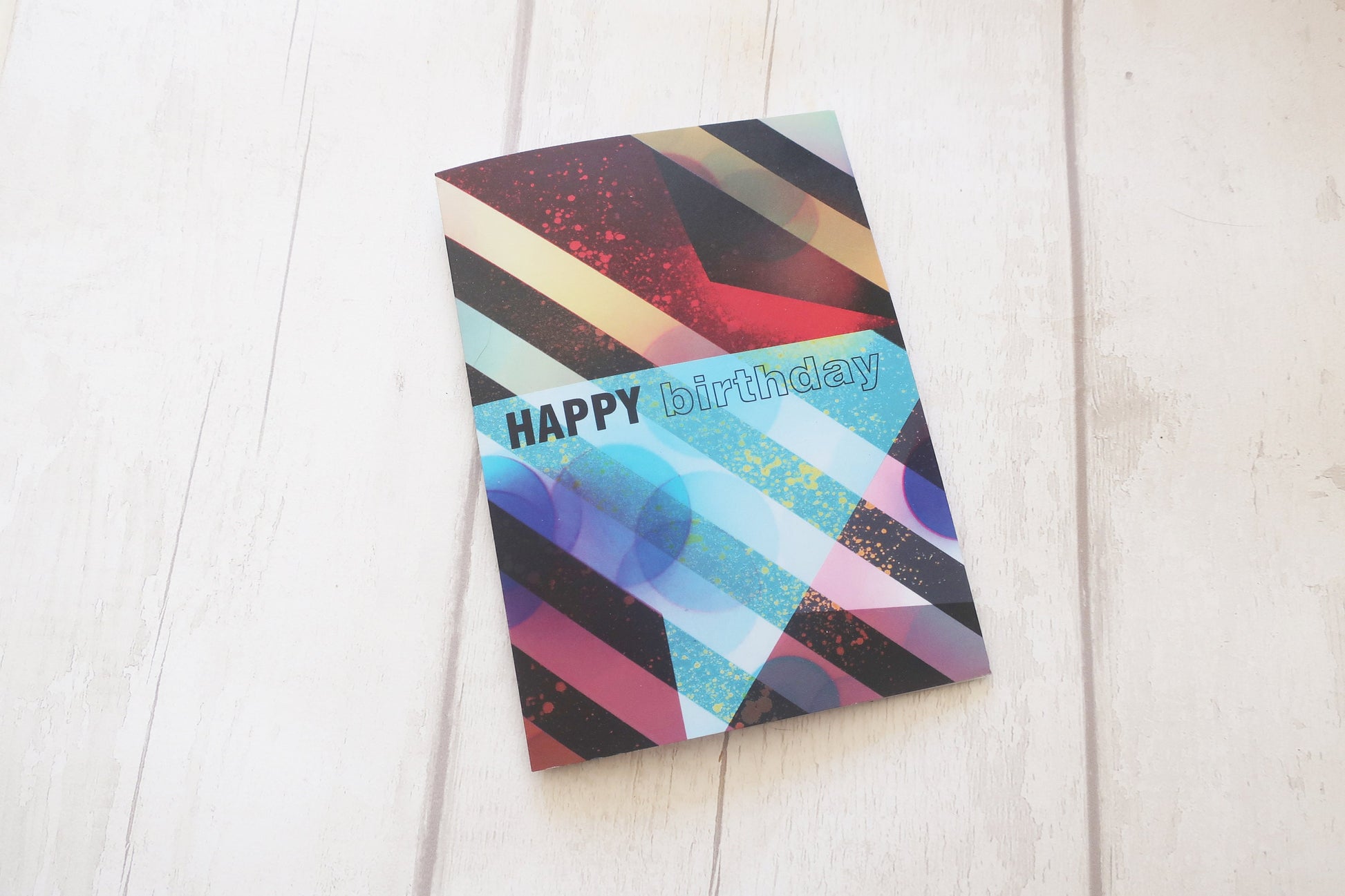 Colorful birthday card with geometric design on a light wooden surface