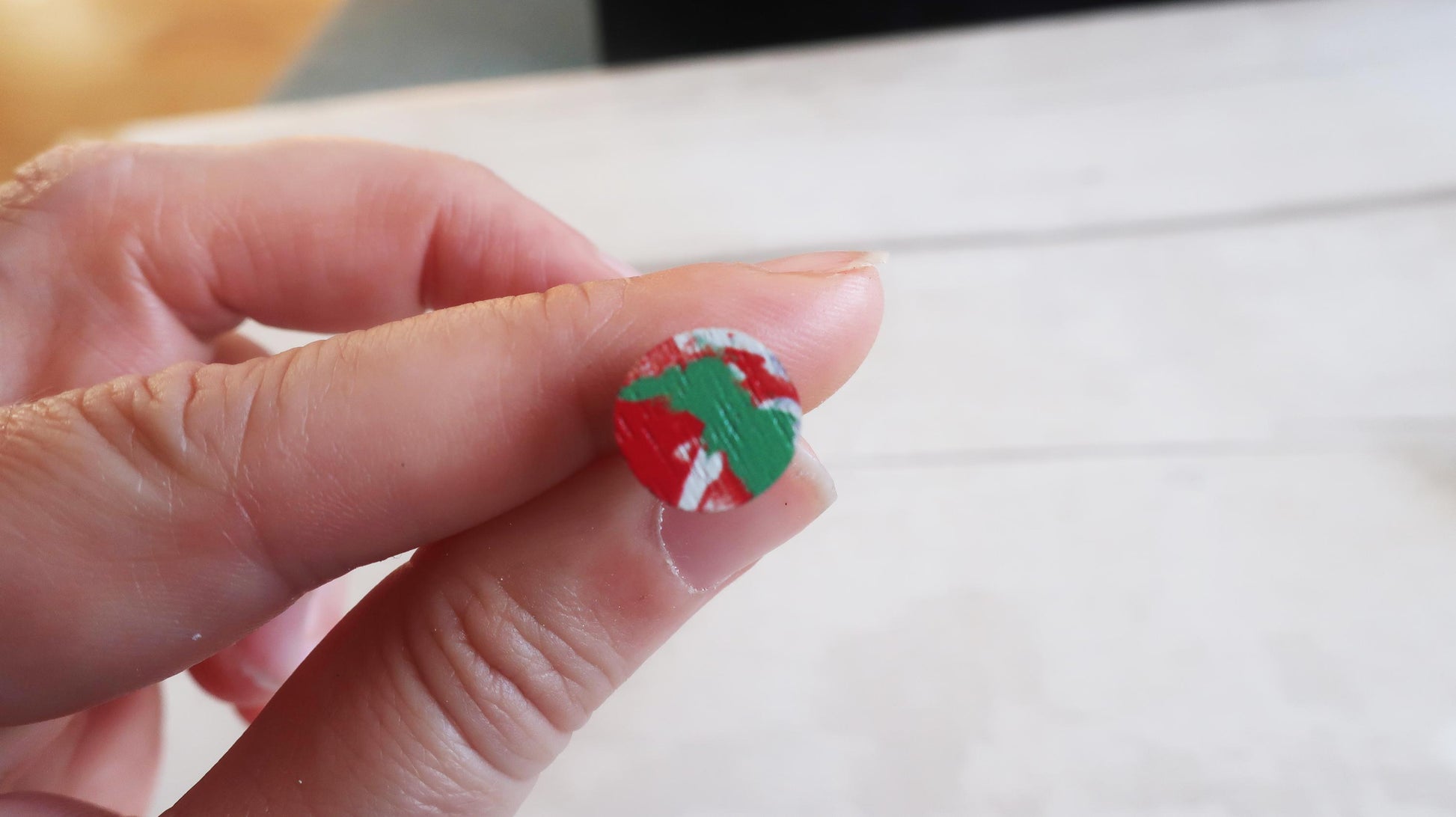 Hand holding a small red and green object against a white background