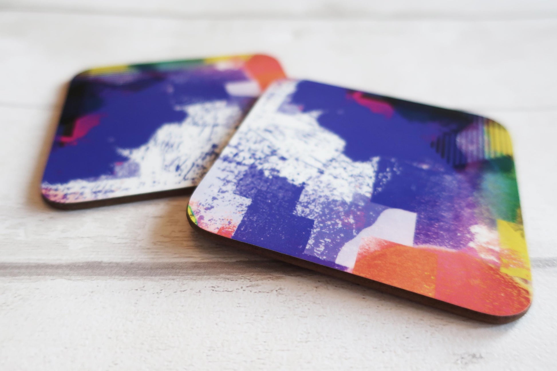 Two colorful coasters on a light wooden surface