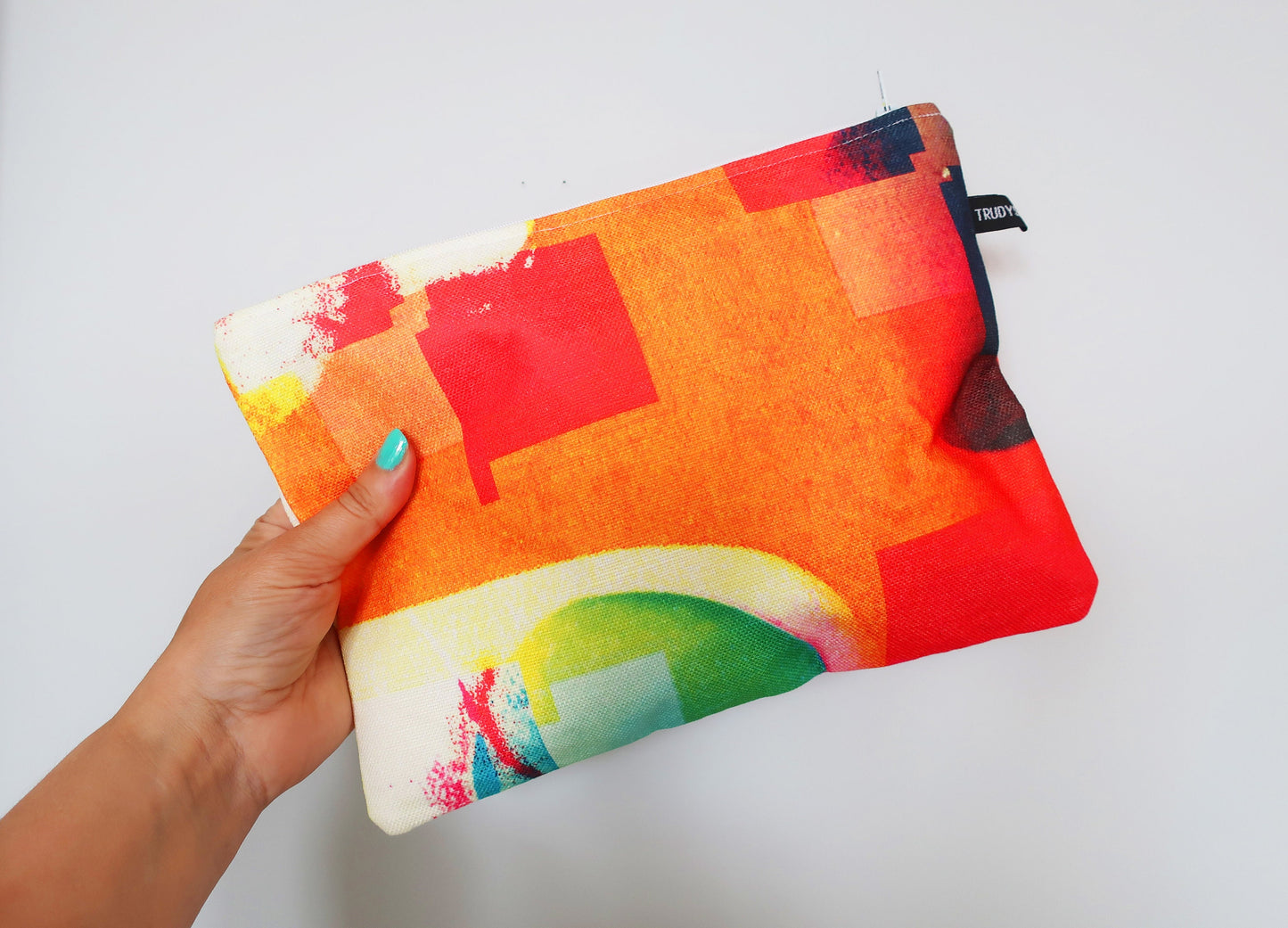 Colorful pouch held by a hand against a white background
