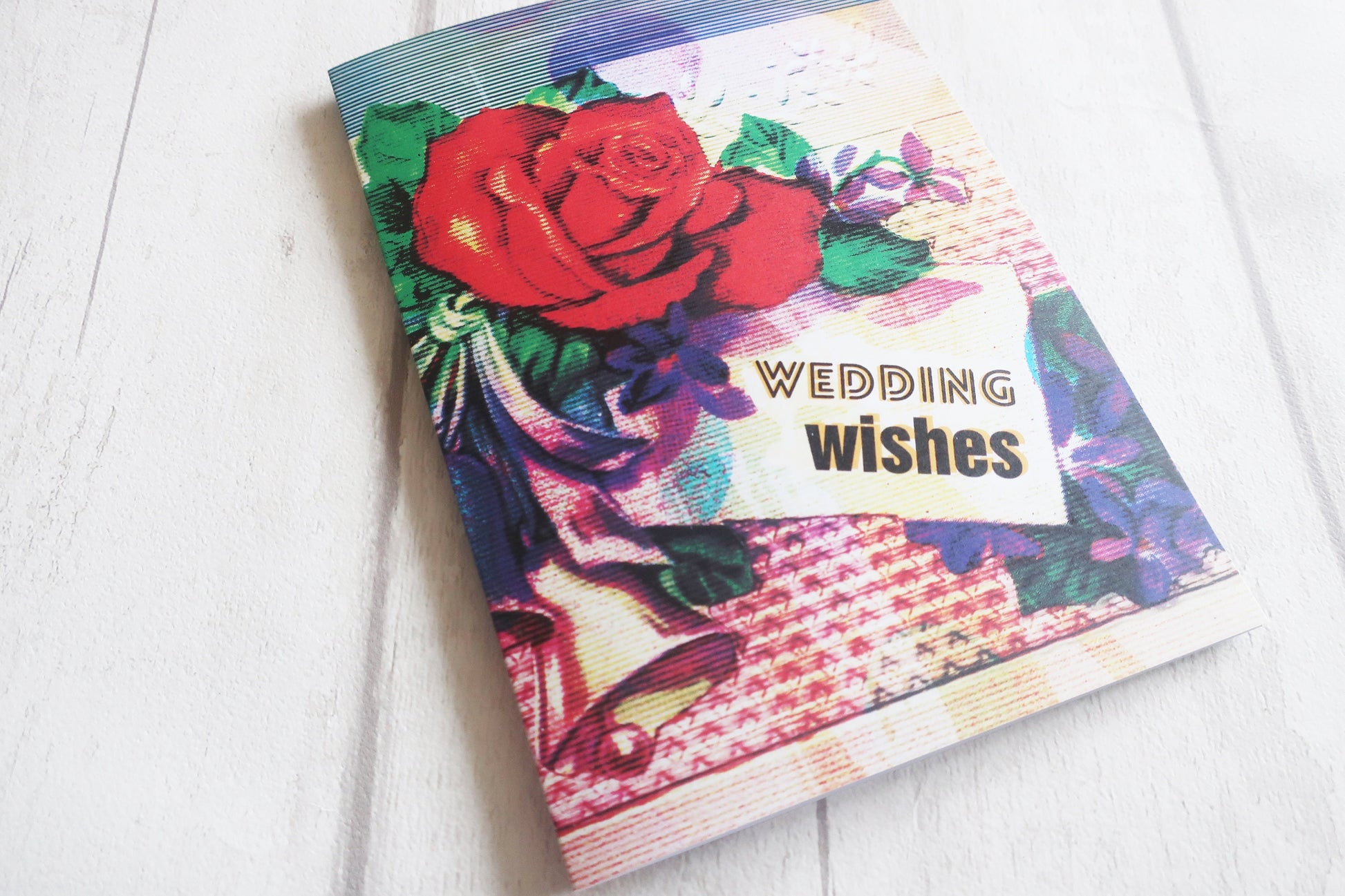 Greeting card with floral design and 'Wedding Wishes' text on a white surface