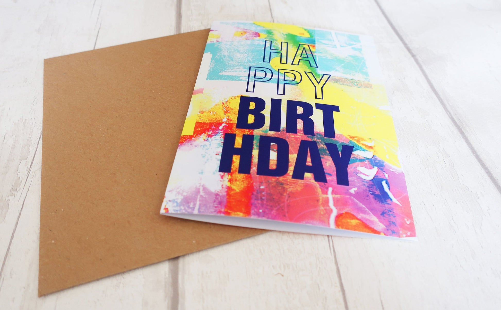 Colorful birthday card with 'Happy Birthday' text on a wooden surface