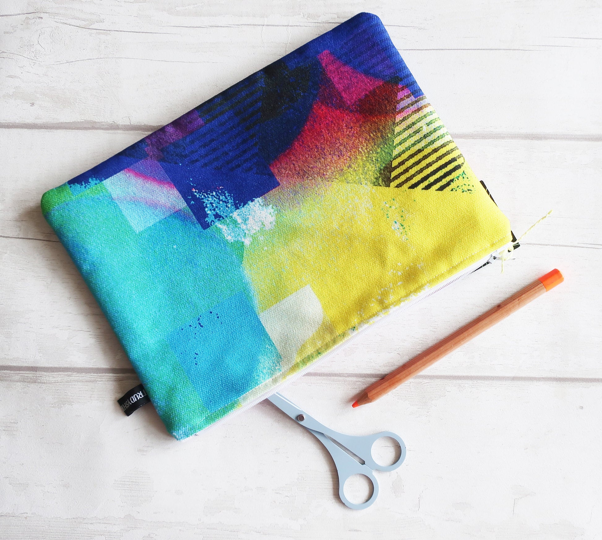 Colorful fabric pouch with a pencil and scissors on a wooden surface