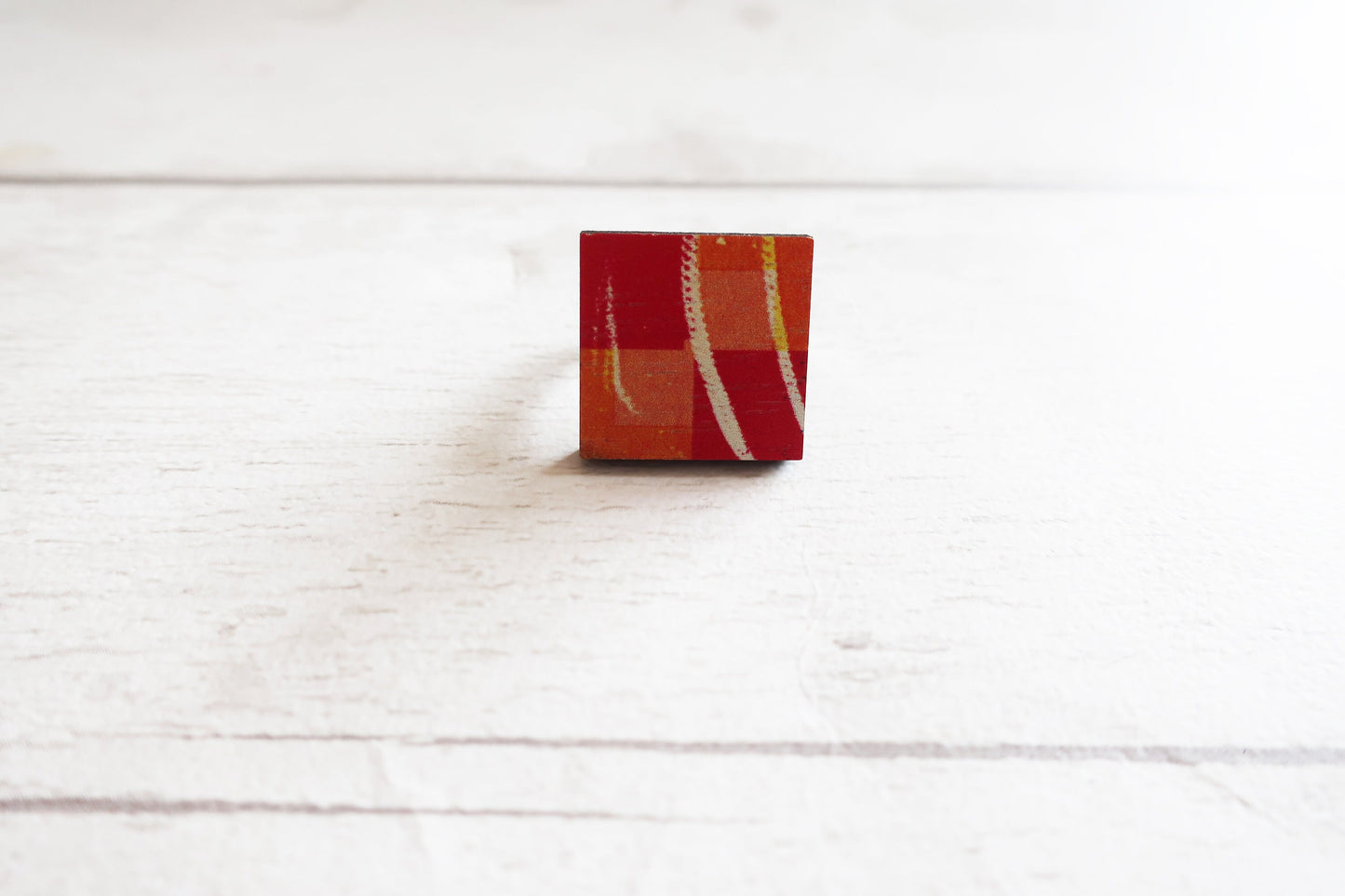 Small rectangular ring with a plaid pattern on a white wooden surface