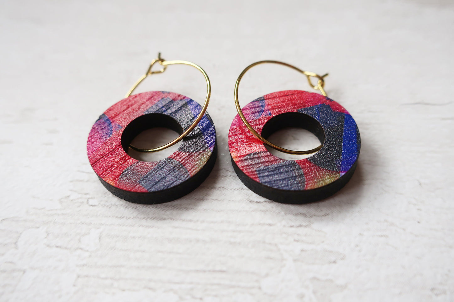 Colorful hoop earrings on a textured white surface