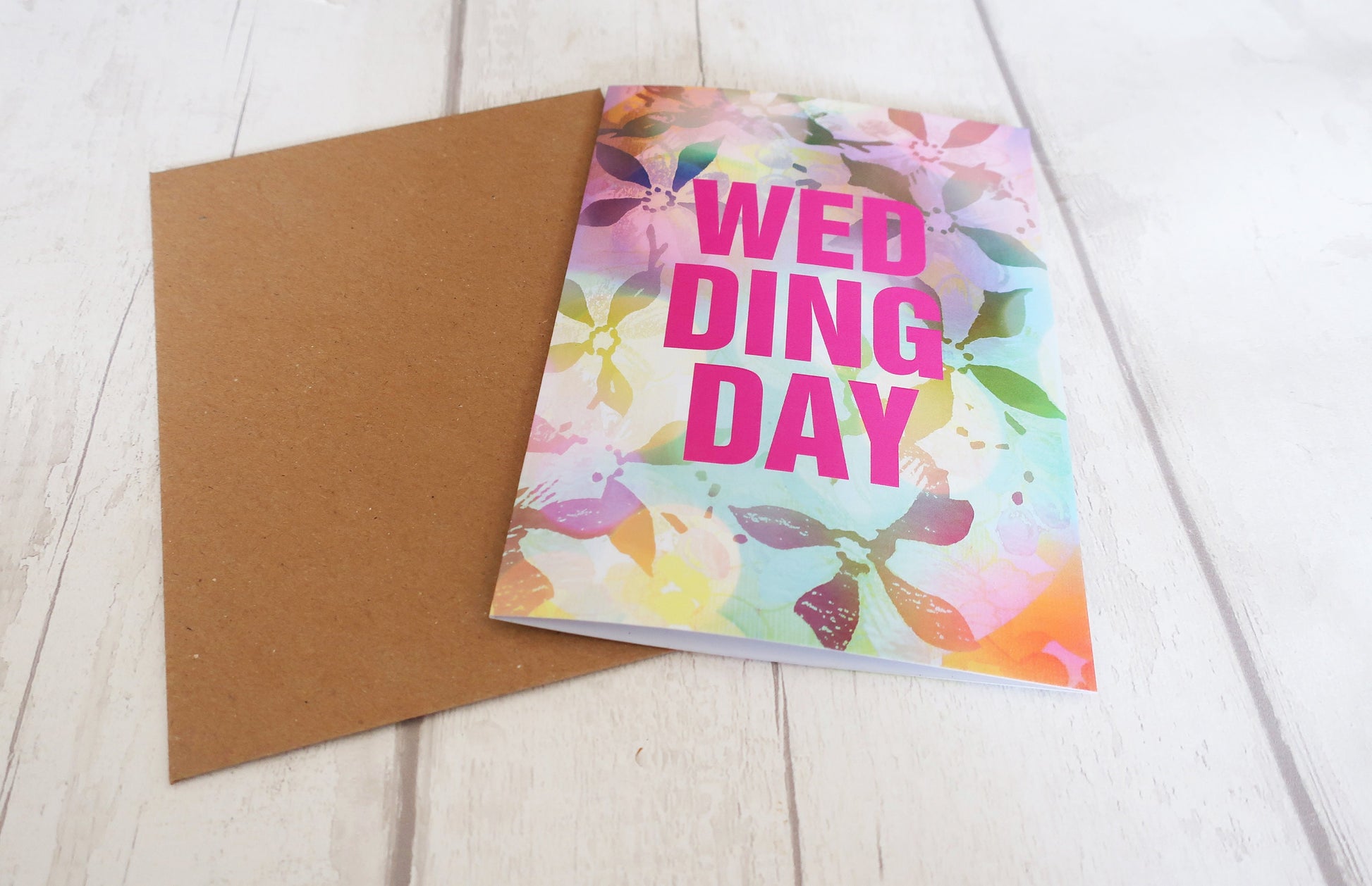 Card with 'Wedding Day' text and floral design on a wooden surface