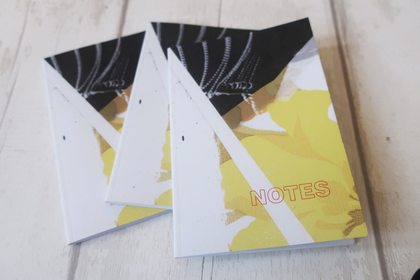 Notebook with a yellow cover and 'NOTES' text on a light wooden surface
