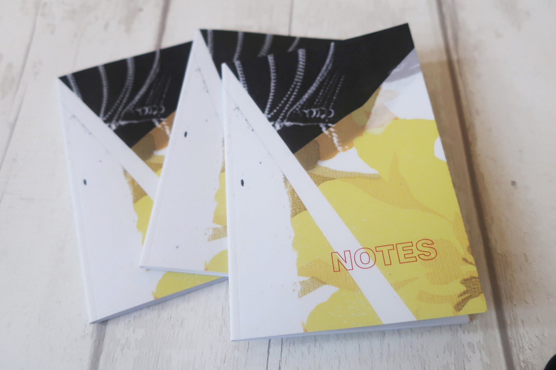 Notebook with a yellow cover and 'NOTES' text on a light wooden surface