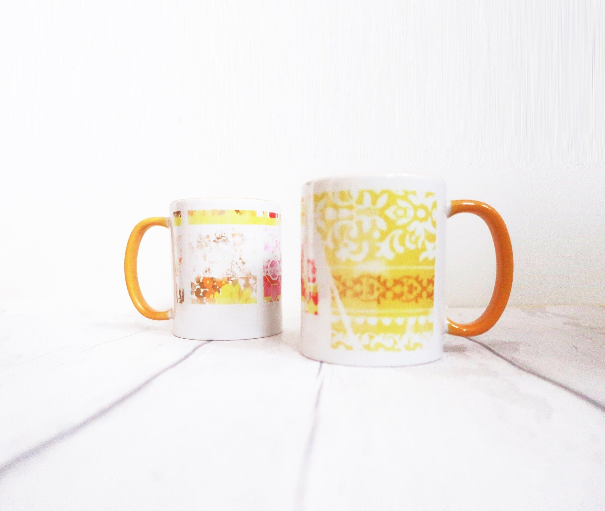 Two mugs with colorful designs on a white surface