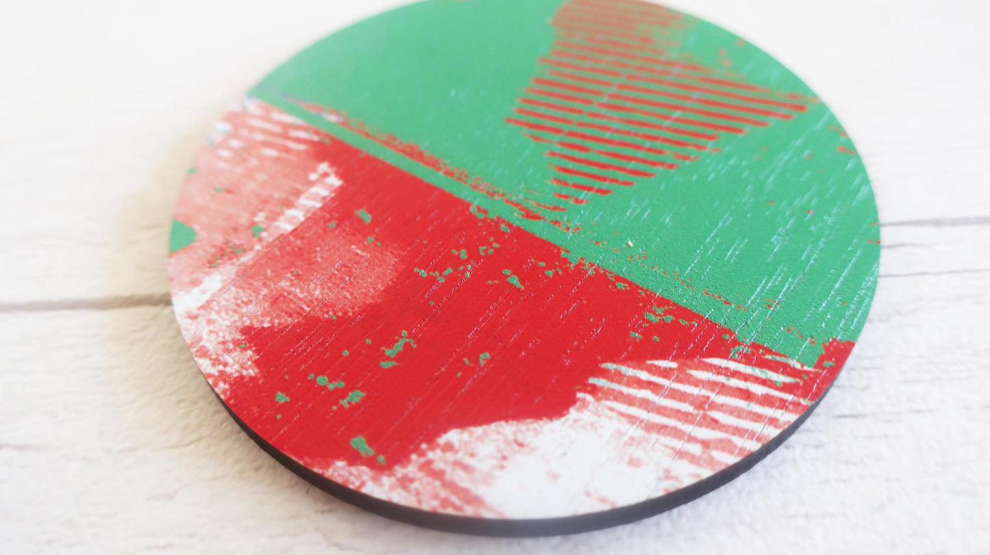 Round brooch with red and green design on a white surface