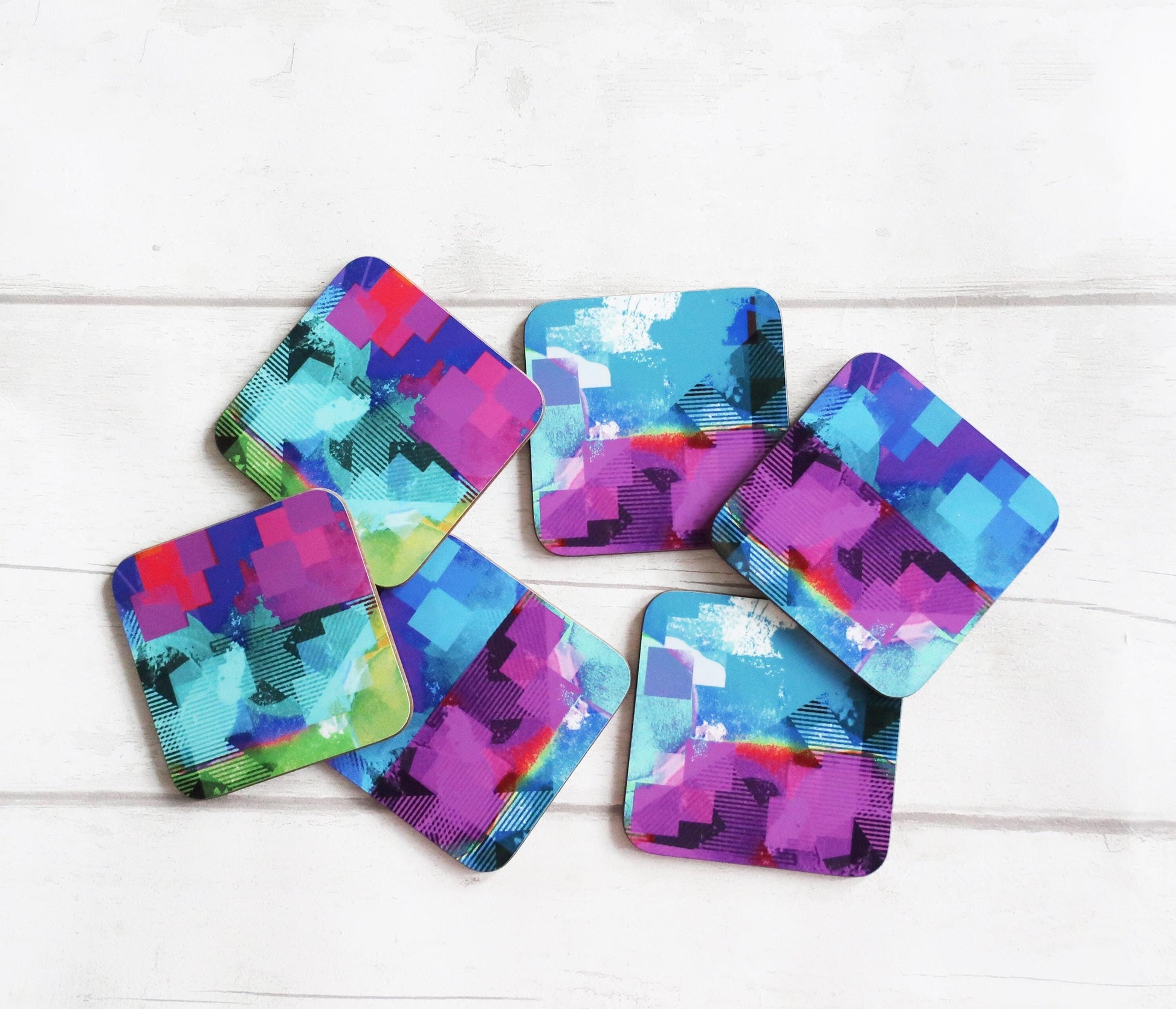 Set of colorful geometric coasters on a white wooden surface