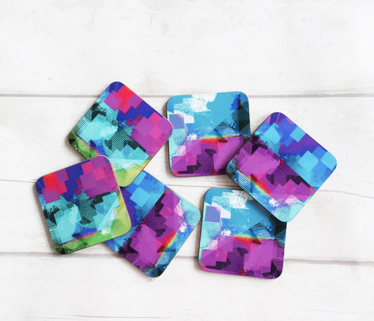 Set of colorful geometric coasters on a white wooden surface