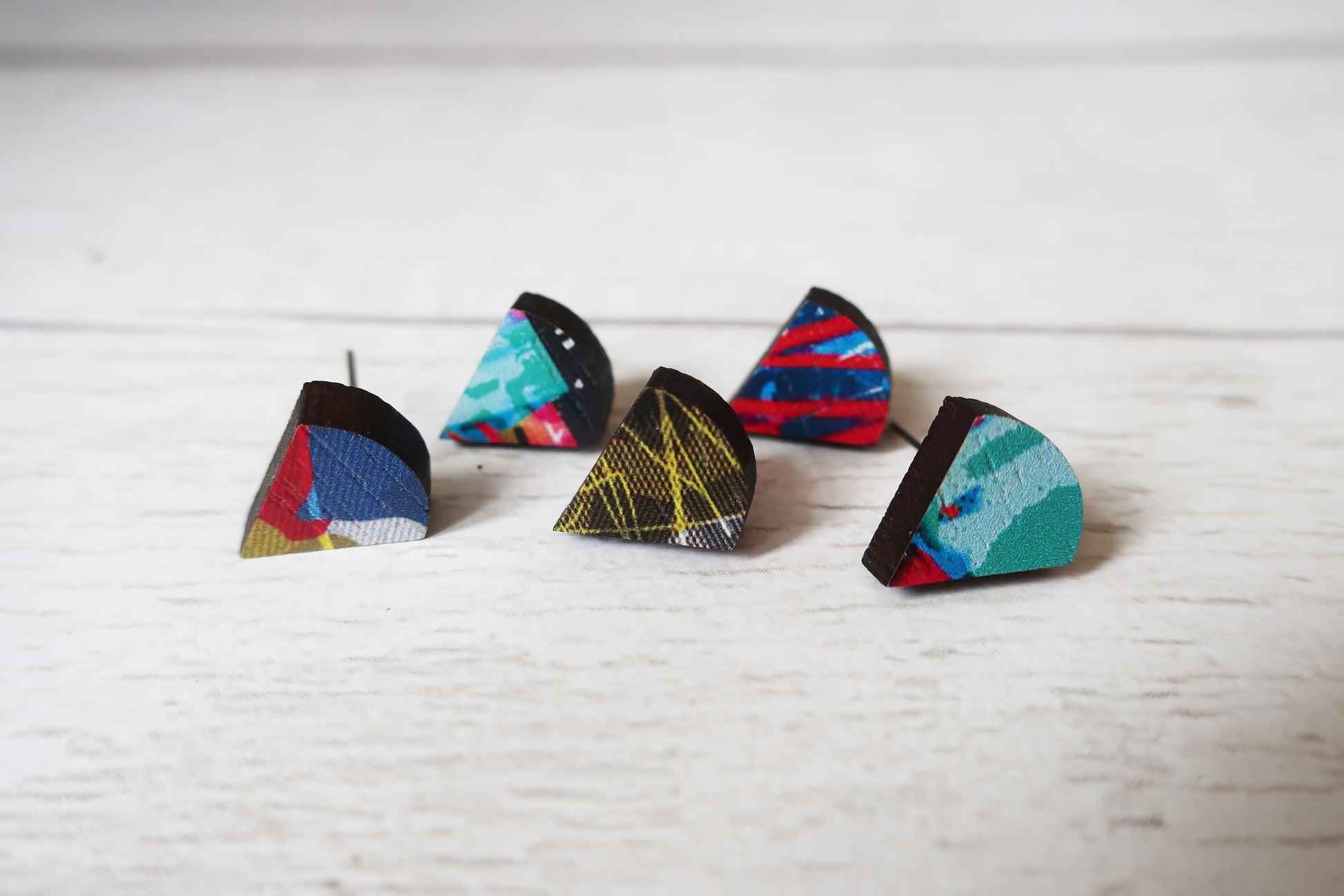 Set of colorful triangle-shaped earrings on a light wooden surface