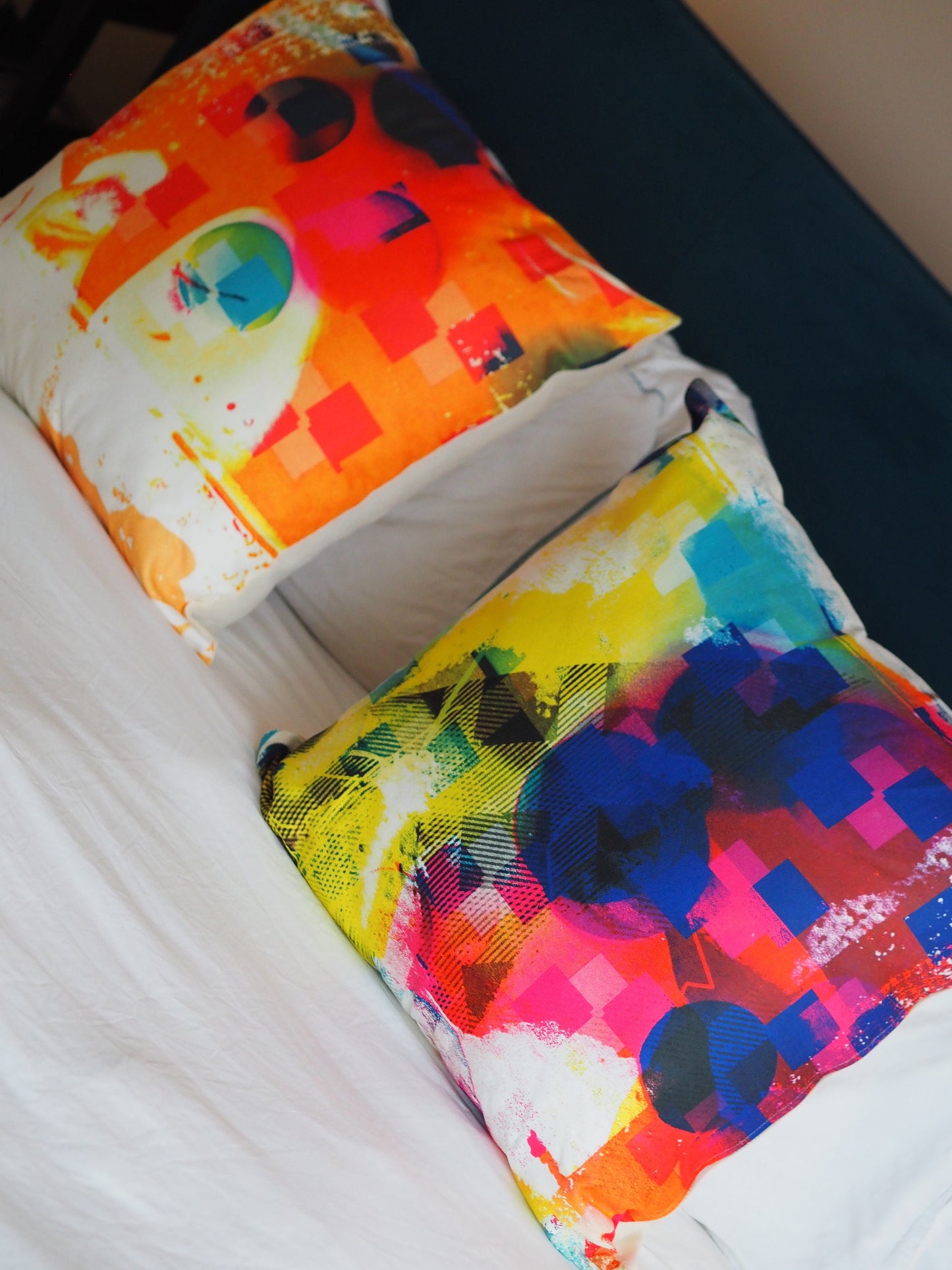 Two Colorful abstract-patterned pillows on a bed