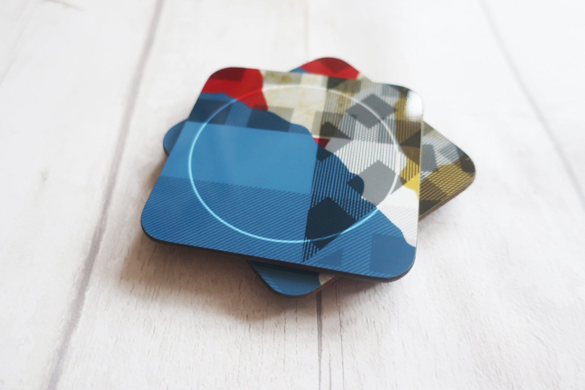 Set of colorful geometric coasters on a light wooden surface