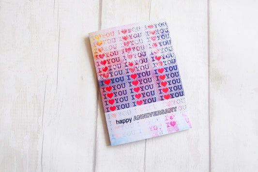 Greetings card with 'I love you' and 'happy anniversary' text on a white wooden surface