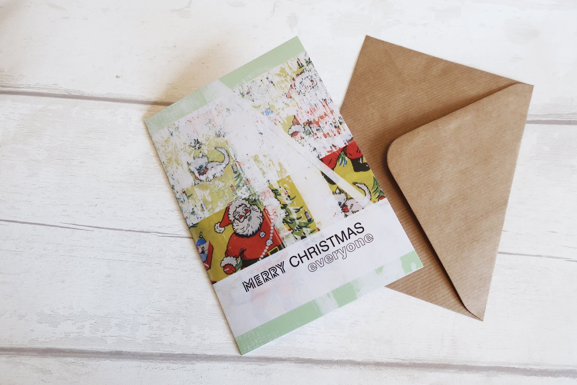 Christmas card with festive design and brown envelope on a white wooden surface