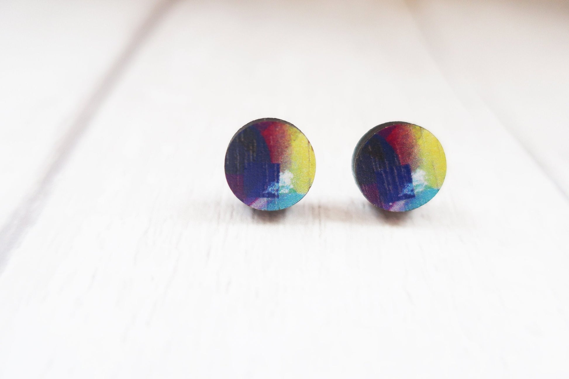 Pair of round rainbow-colored earrings on a white background
