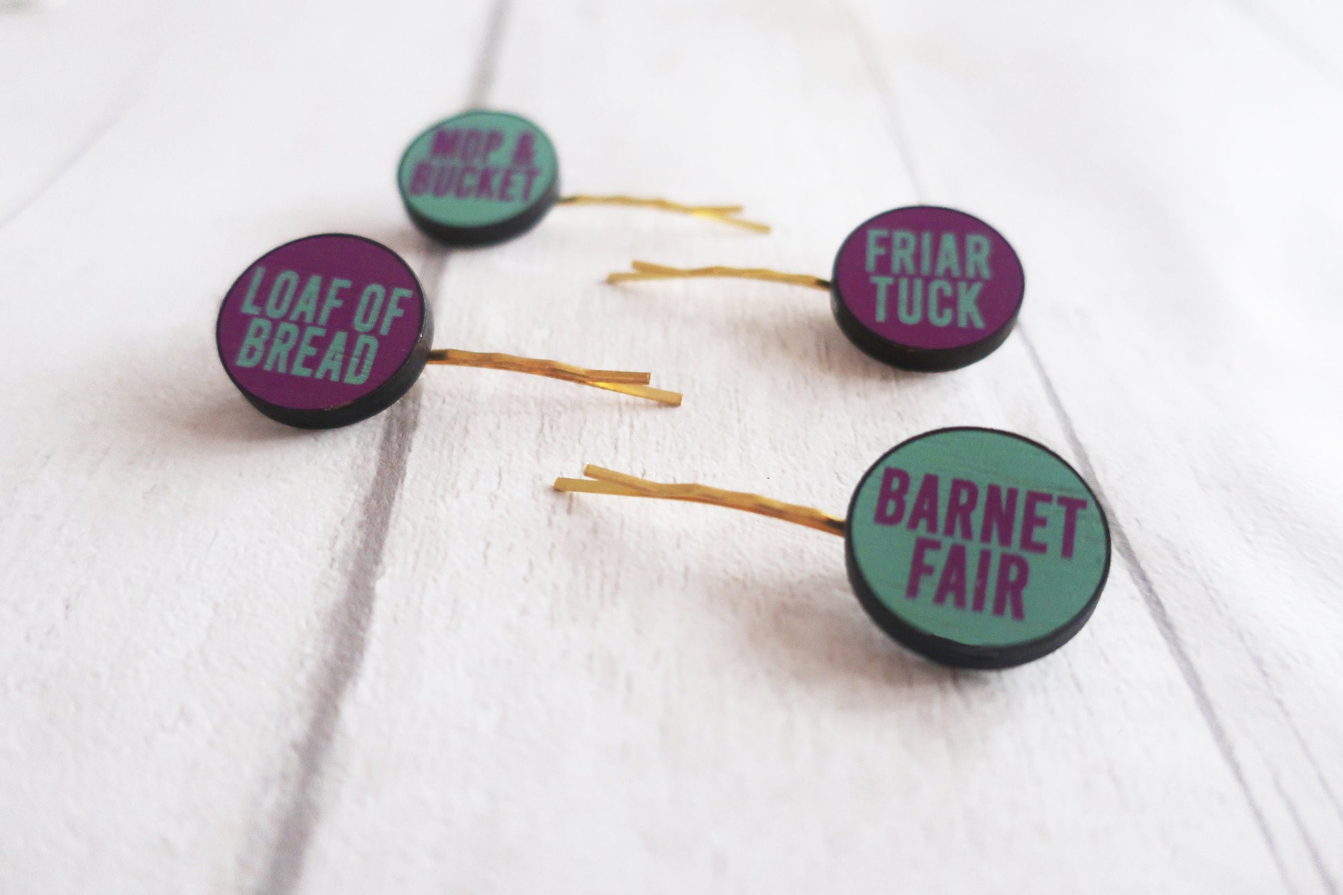 Set of hair pins with purple and green text on a white background
