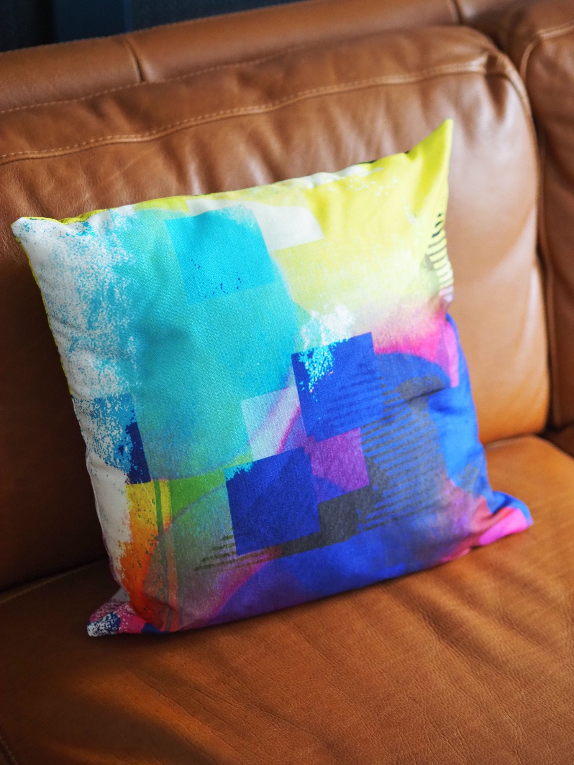Colorful abstract-patterned pillow on a brown leather couch
