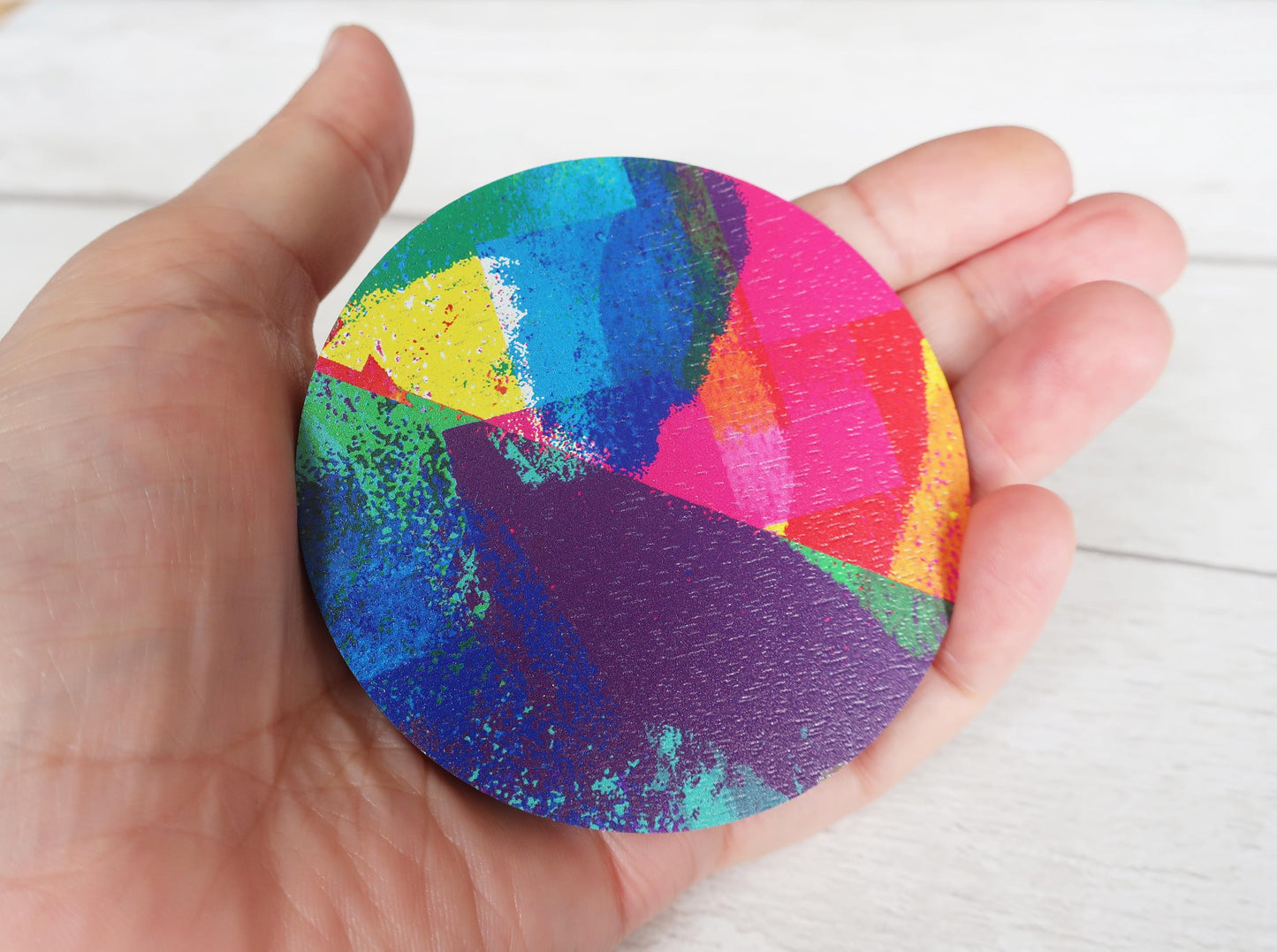 Hand holding a colorful circular brooch