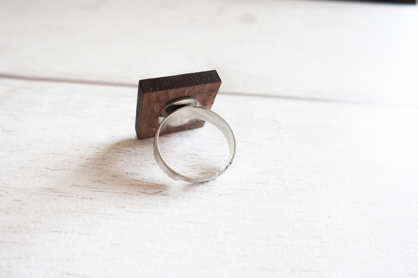 Silver ring with a wooden base on a white surface