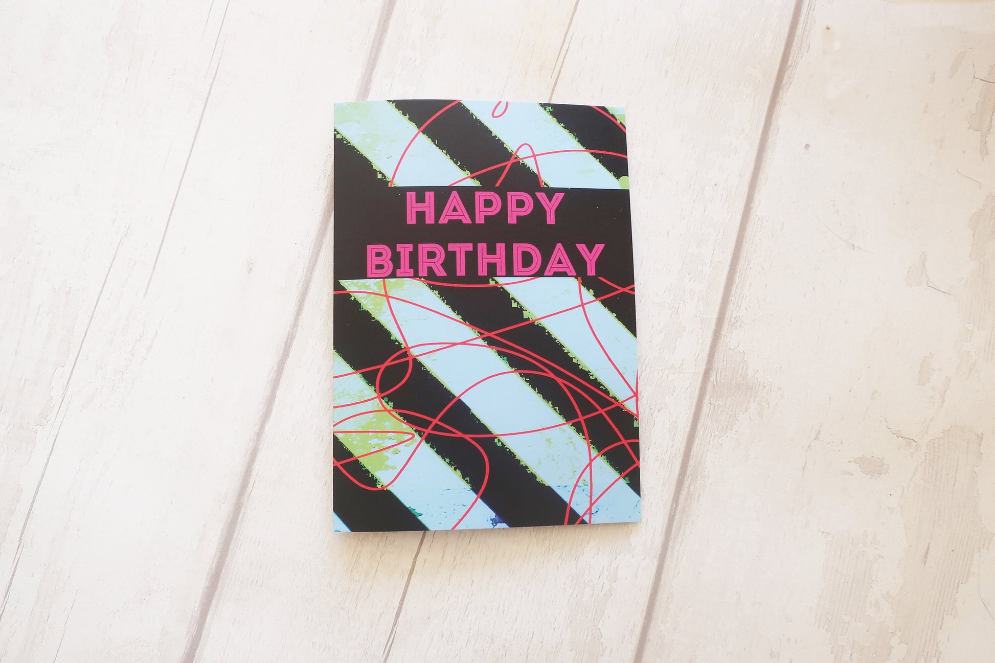Birthday card with geometric design and 'Happy Birthday' text on a wooden surface