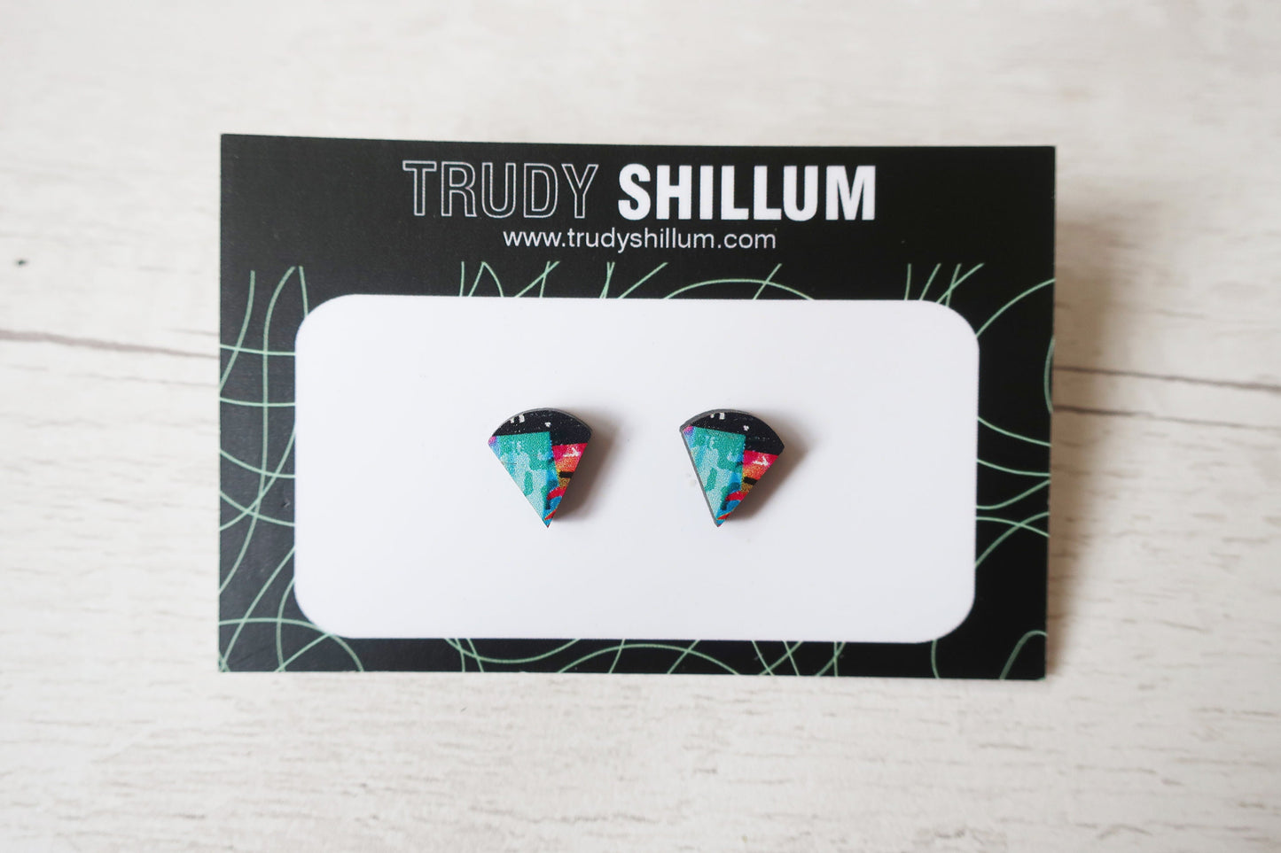 Pair of colorful triangular earrings on a Trudy Shillum branded card.