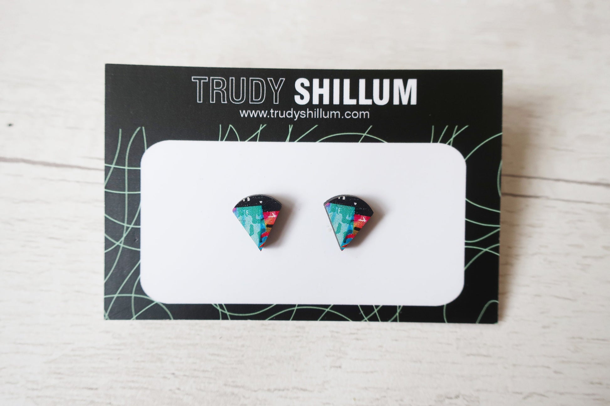 Pair of colorful triangular earrings on a Trudy Shillum branded card.