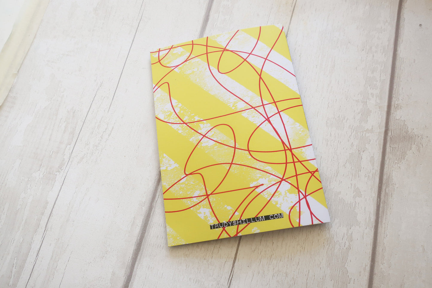 Yellow card back with red and white abstract patterns on a light wooden surface
