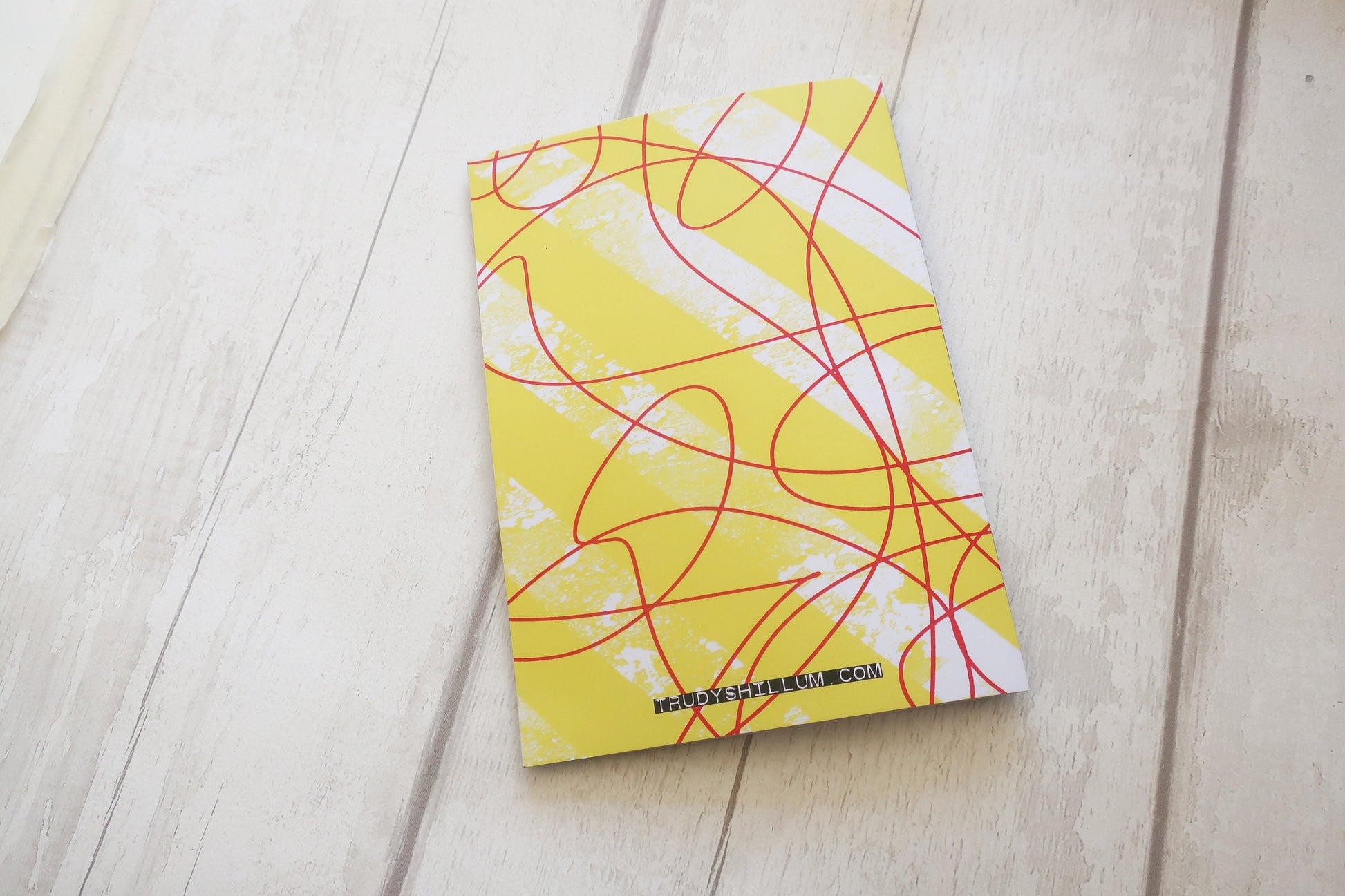 Yellow card back with red and white abstract patterns on a light wooden surface