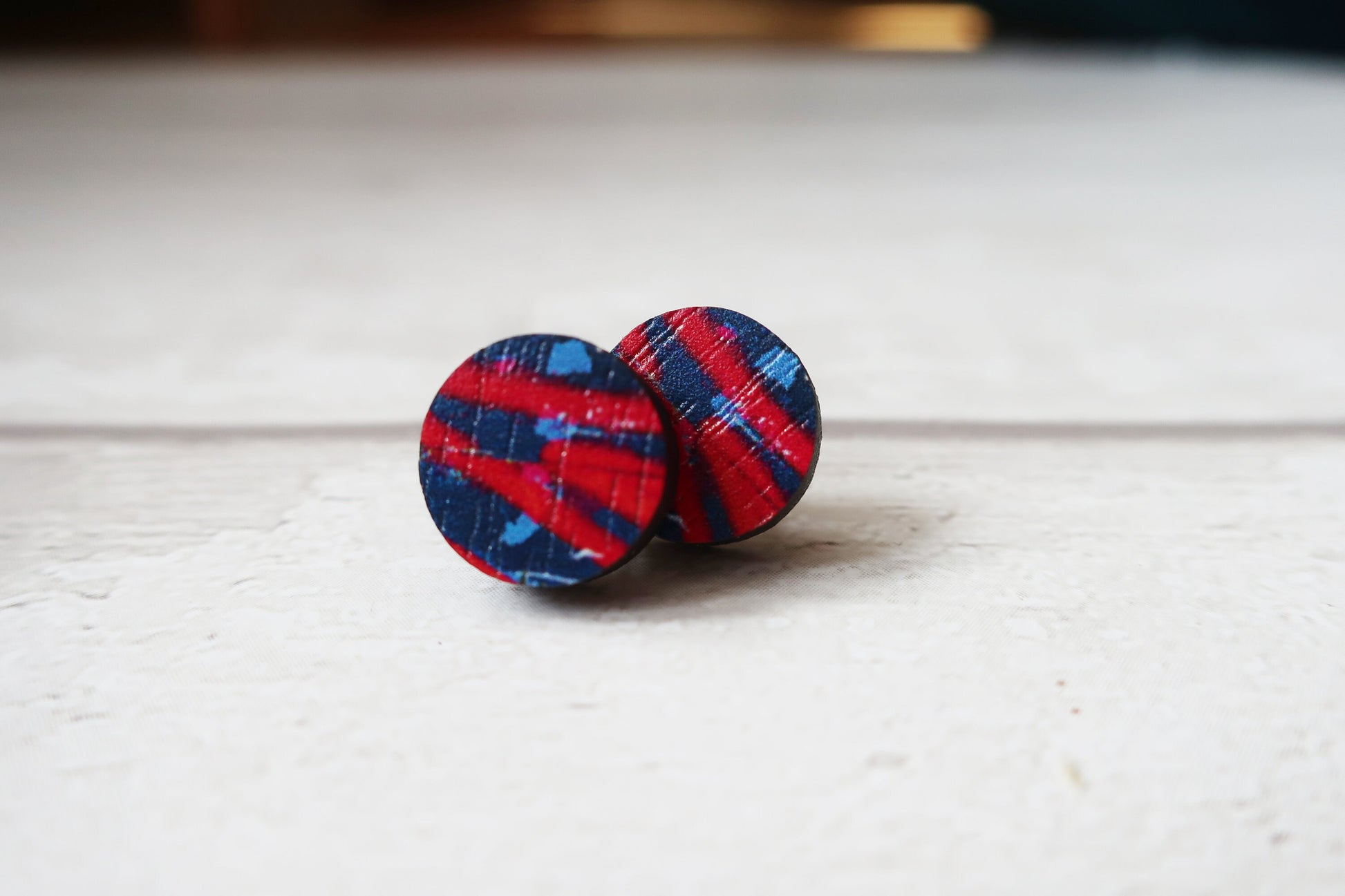 Plaid patterned earrings on a light wooden surface