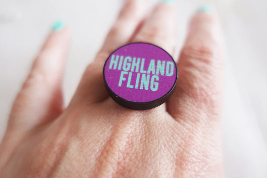 Purple ring with 'Highland Fling' text on a hand against a white background