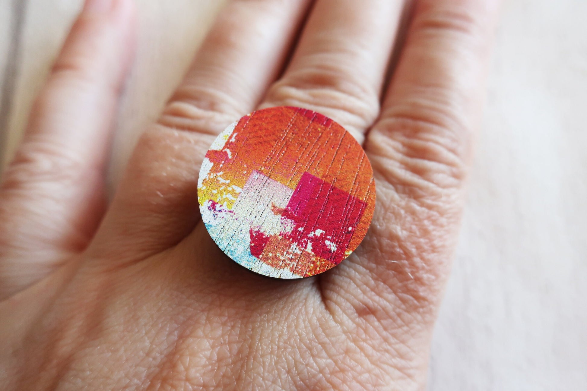 Colorful ring with a circular design on a hand against a neutral background