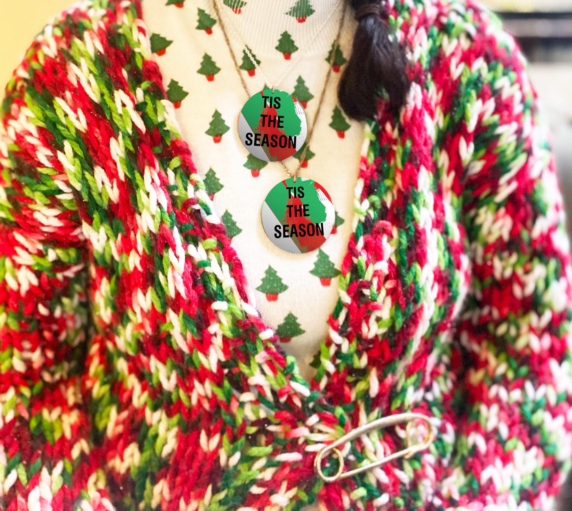 Red, green, and white striped cardigan with 'Tis the Season' necklaces on a mannequin.