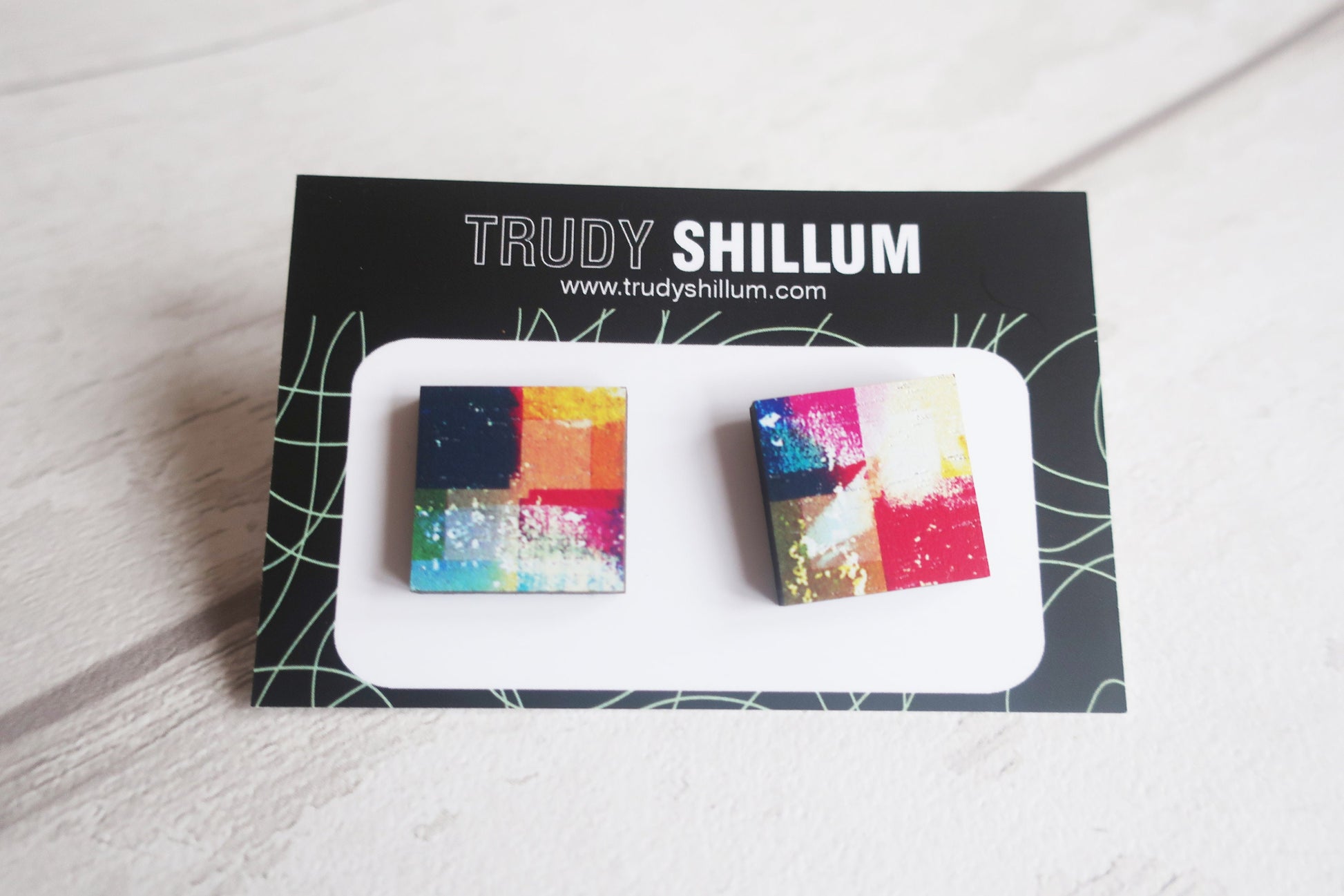 Colorful square earrings on a Trudy Shillum branded card.