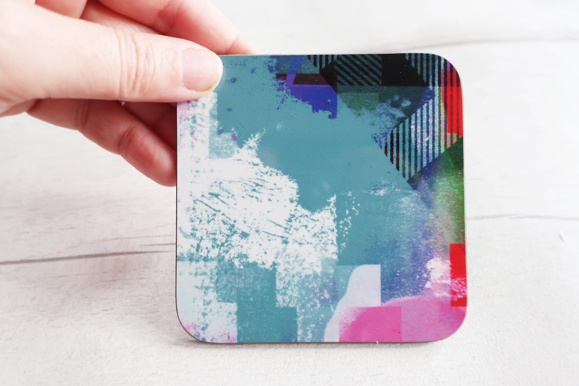 Colorful abstract coaster held by a hand on a light background