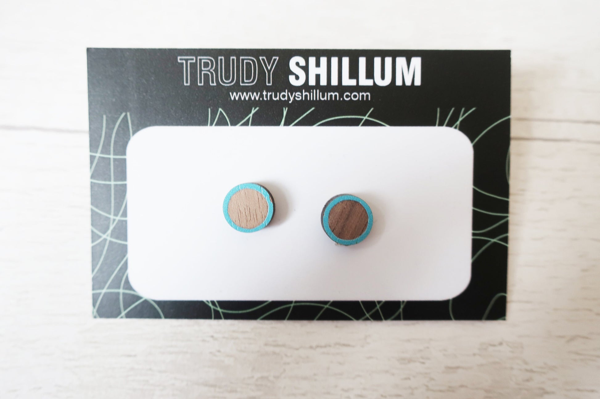 Pair of earrings on a Trudy Shillum branded card with a white background