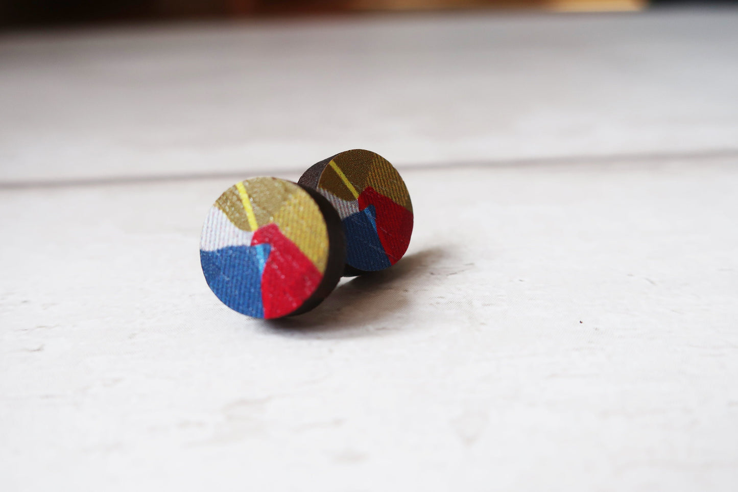 Colorful circular earrings on a light wooden surface