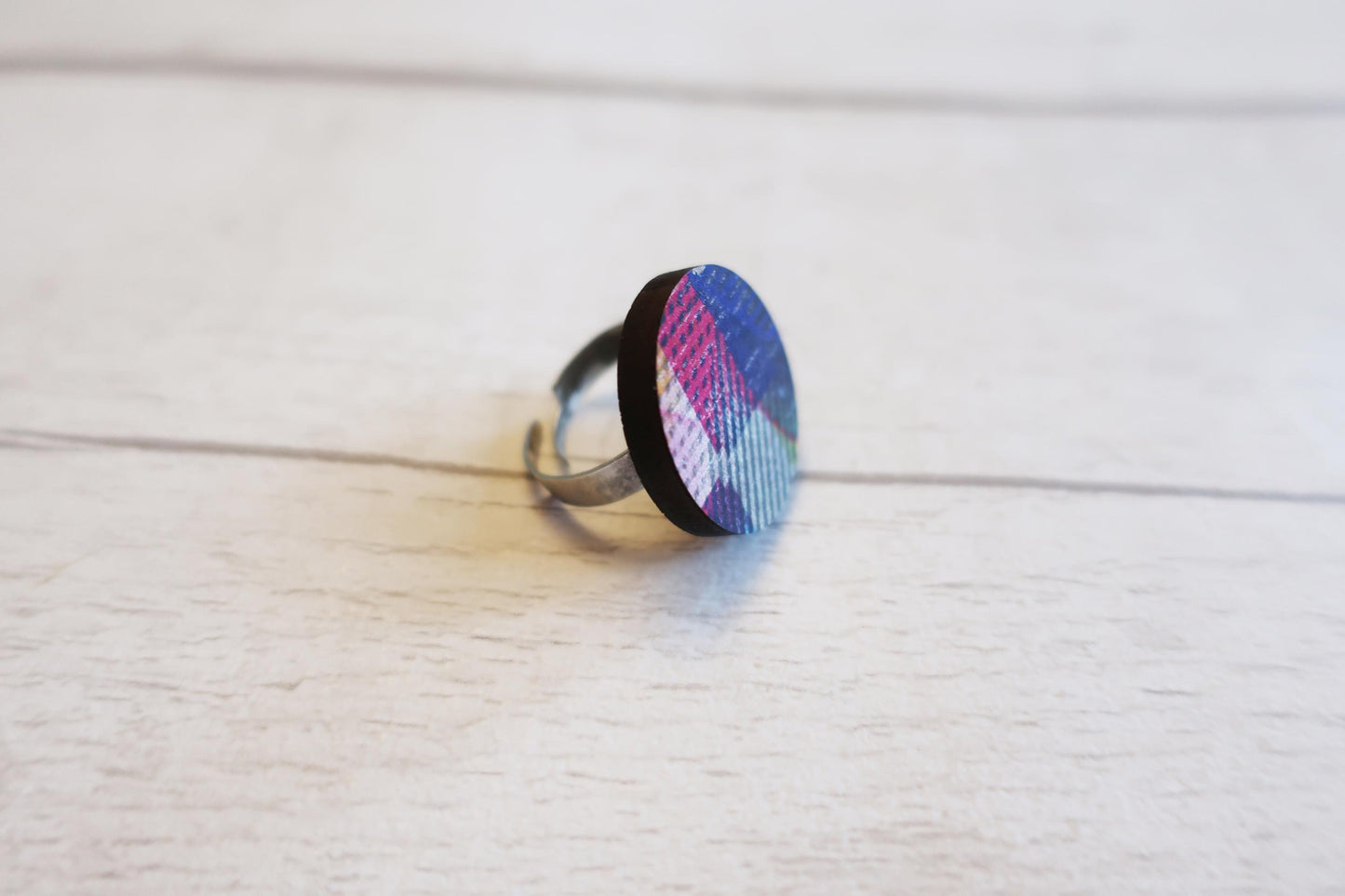 Ring with a colorful geometric design on a light wooden surface