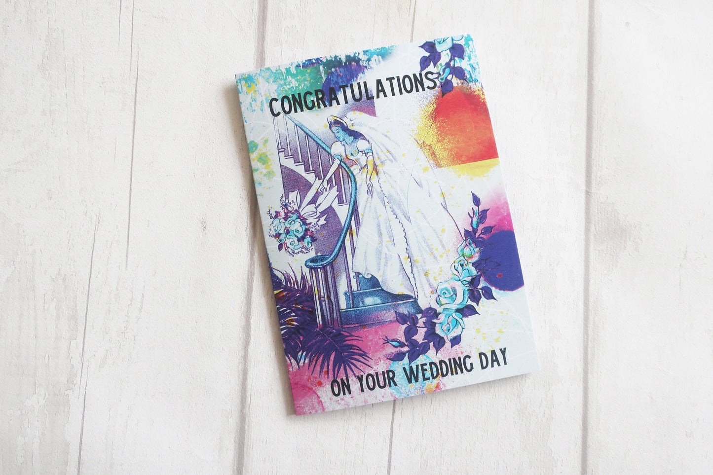Wedding card with colorful design on a white wooden surface
